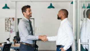 Two people shaking hands happily in an office, reflecting a positive work environment